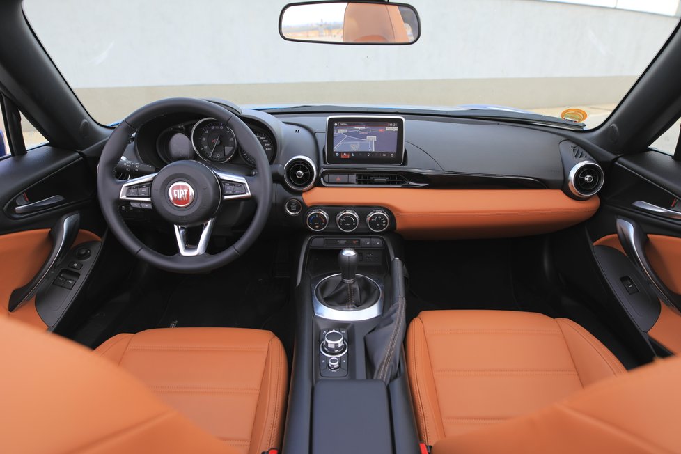 Sportovně těsný a kvalitně zpracovaný interiér se od dárcovské Mazdy MX-5 liší jen znakem. Multimediální systém má svérázné menu a ovládání z ruky na tunelu mezi sedadly.